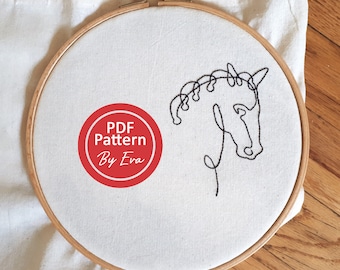 May include: A white embroidery hoop with a black line drawing of a horse's head. The hoop has a red circle with the text "PDF Pattern By Eva" in white.