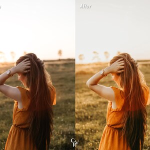 May include: A woman with long, red hair is wearing a mustard yellow dress and a gold watch. She is standing in a field of tall grass with a sunset in the background.