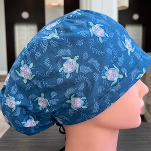 May include: Blue scrub hat with a pattern of colorful sea turtles and leaves.