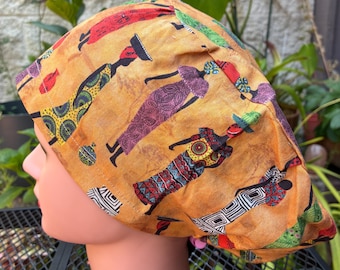 Könnte beinhalten: Eine gemusterte OP-Haube mit einem sich wiederholenden Design von stilisierten Figuren in verschiedenen farbenfrohen Outfits. Der Hintergrund der Haube ist ein warmes, goldbraunes. Die Figuren sind in Rot-, Grün-, Lila- und Gelbtönen gehalten.