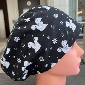 May include: Black scrub hat with a white squirrel print. The hat has a white elastic band and a white drawstring.