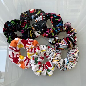 May include: Set of six colorful hair scrunchies with various school-themed prints, including apples, pencils, and scientific formulas.