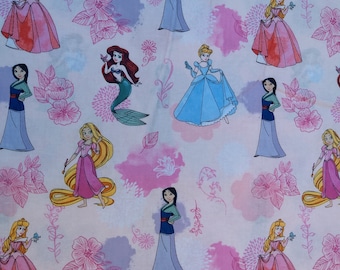 Può includere: Un tessuto rosa e bianco con un motivo ripetitivo di principesse Disney. Le principesse includono Cenerentola, Ariel, Belle, Mulan, Rapunzel e Aurora. Il tessuto è decorato con disegni acquerellati rosa e blu e motivi floreali.