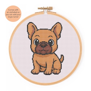 Può includere: Un kit per punto croce con un cucciolo di bulldog francese a cartoni animati. Il disegno è nei toni del marrone e del nero, su uno sfondo rosa chiaro all'interno di un telaio da ricamo in legno. Il testo sull'immagine dice: "Viene con un alfabeto in modo da poter aggiungere il nome del tuo cane!"