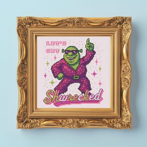 Könnte beinhalten: Kreuzstichkunst von Shrek in einem Disco-Outfit, mit Sonnenbrille und nach oben zeigend. Der Text lautet "Let's Get Shwrecked" in Pink und Grün. Das Kunstwerk ist in einem goldenen, verzierten Rahmen gerahmt.