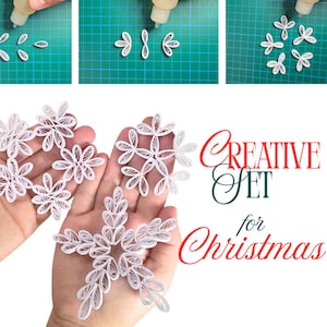 Op de afbeelding: Een knutselhandleiding die het maken van papieren sneeuwvlokken demonstreert. De afbeelding toont het proces van het in elkaar zetten van witte papieren sneeuwvlokken met lijm. De tekst "Creative Set for Christmas" wordt in rood en groen weergegeven.