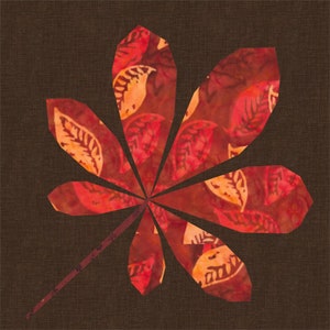 May include: A red and orange leaf with a brown background. The leaf is made of fabric and has a patchwork design.