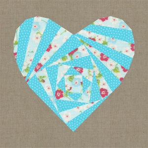 May include: A heart-shaped quilt block with a light blue and white polka dot pattern and floral print. The heart is constructed from geometric shapes and set against a neutral background.