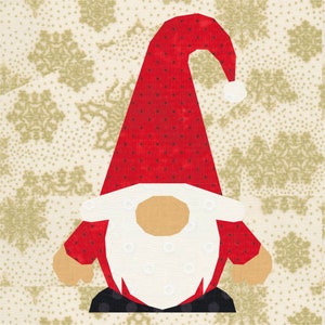 May include: A fabric Christmas gnome with a red hat and body, white beard, and tan face. The gnome is set against a background of cream-coloured fabric with a snowflake pattern. The gnome's hat has small black dots.