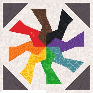 May include: A colorful quilt block featuring a pinwheel design. The pinwheel is composed of various patterned fabrics in shades of red, orange, yellow, green, blue, purple, brown, and black. The block is set against a white background with a floral pattern and gray corner accents.