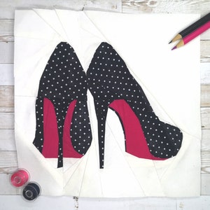 May include: Two black high-heeled shoes with white polka dots and red heels. The shoes are made of fabric and are arranged on a white background.