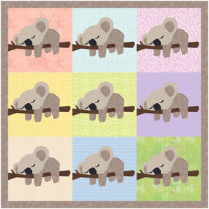 K&ouml;nnte beinhalten: Ein Quiltblock mit neun Quadraten, die ein sich wiederholendes Muster eines schlafenden Koalas auf einem Ast zeigen. Die Quadrate sind in abwechselnden Farben rosa, hellblau, gelb, gr&uuml;n und hellblau.