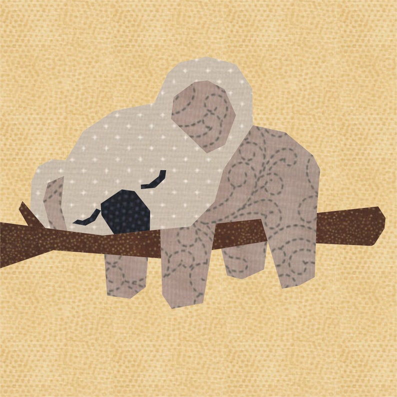 K&ouml;nnte beinhalten: Ein grauer Koalab&auml;r mit brauner Nase und schwarzen Augen schl&auml;ft auf einem braunen Ast. Der Koala ist aus Stoff gefertigt und hat ein gesticktes Muster.