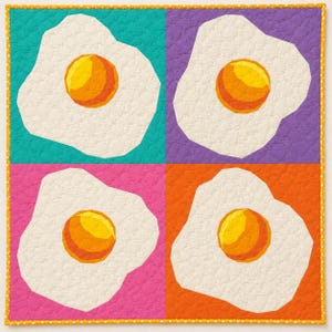 May include: A colorful quilt featuring four fried egg designs. Each egg has a yellow yolk and a white egg white, set against teal, purple, pink, and orange backgrounds. The quilt is bordered with a yellow dotted fabric.