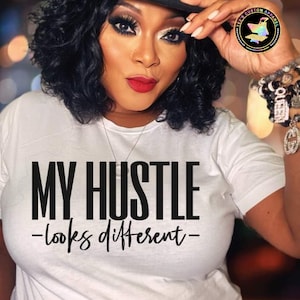 May include: A white t-shirt with black text that reads "MY HUSTLE -looks different- "