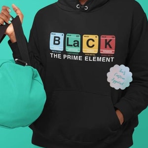 May include: Black hoodie with a graphic of the periodic table elements spelling out "Black" with the text "The Prime Element" below. The hoodie is black with a white drawstring and a small logo on the bottom right corner that says "Kes Custom Apparel".