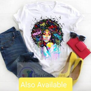 May include: White t-shirt with a colorful graphic print of a woman with an afro hairstyle. The graphic includes words like "Dream" and "Love".