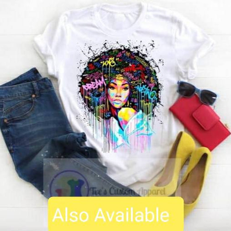 May include: White t-shirt with a colorful graphic print of a woman with an afro hairstyle. The graphic includes words like "Dream" and "Love".