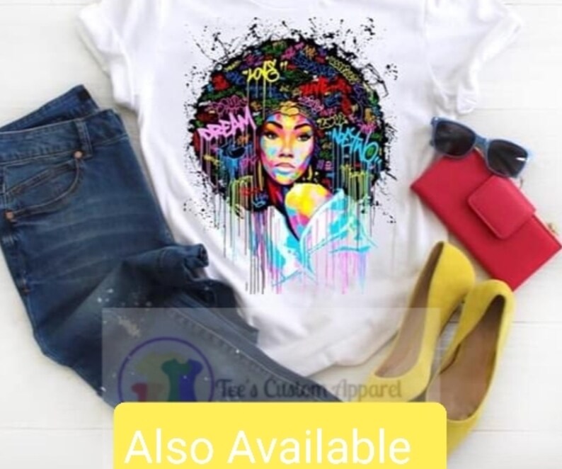 May include: White t-shirt with a colorful graphic of a woman with an afro hairstyle. The graphic includes colorful paint splatters and the words "Dream" and "108".