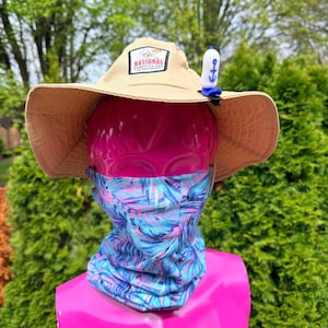 Puede incluir: Un sombrero para el sol de color beige con un parche que dice "National Coney Island Since 1966" se muestra en una cabeza de maniqu&iacute; rosa. El sombrero tiene un clip de ancla azul y blanco. Tambi&eacute;n se usa un polaina para el cuello con estampado azul, rosa y blanco.