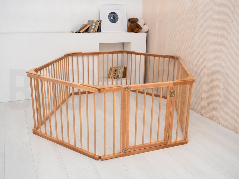 Pu&ograve; includere: Un box per bambini esagonale in legno con un cancello. Il box &egrave; realizzato in legno naturale e ha una finitura marrone chiaro. Il cancello &egrave; incernierato e ha un chiavistello.