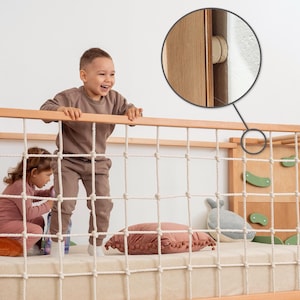 Pu&ograve; includere: Un letto per bambini in legno con parete da arrampicata, rete di corda e scala. La struttura del letto &egrave; marrone chiaro con accenti verdi. Due bambini giocano sul letto. Il letto ha un materasso color crema e un cuscino rosa.