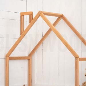 May include: A wooden playhouse frame with a simple design, made of natural wood. The frame is unfinished and ready to be painted or stained. A teddy bear sits inside the frame.