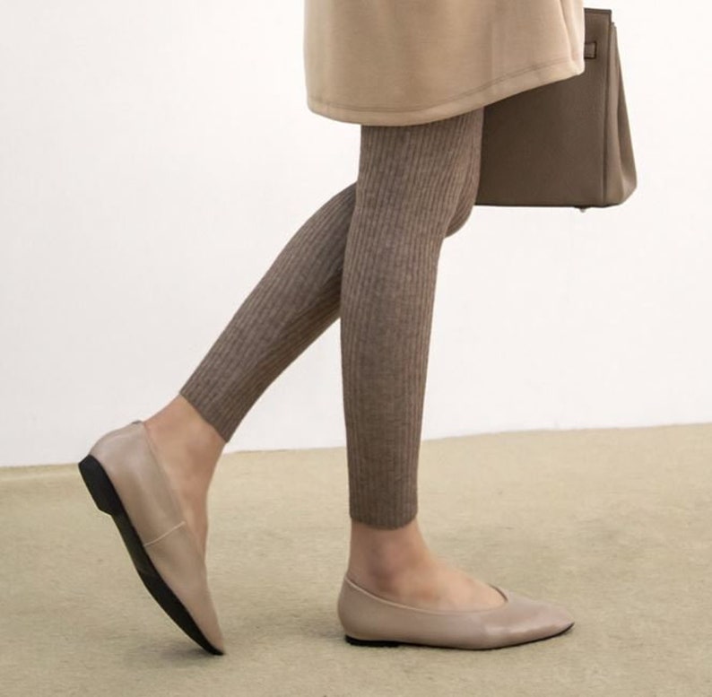 Puede incluir: Bailarinas color topo con punta y suela negra. Se combinan con leggings de punto acanalado en un tono marr&oacute;n similar. Un abrigo beige y un bolso marr&oacute;n completan el conjunto.