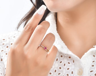 May include: A gold ring with a red gemstone and small diamonds set in the band.