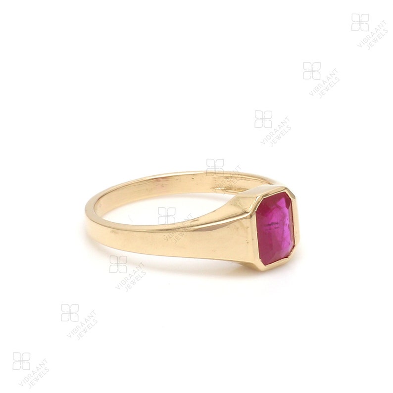 May include: A gold ring with a large, rectangular, dark pink gemstone.