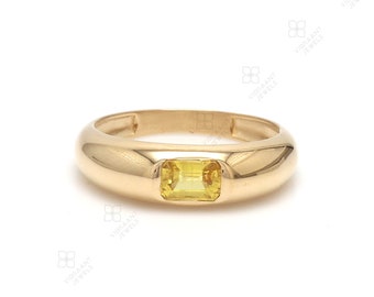 May include: A gold ring with a yellow gemstone set in the center. The ring has a smooth, rounded band.
