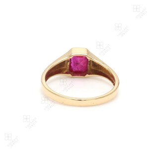 May include: A gold ring with a large, square-shaped, red gemstone set in the center. The ring has a simple, classic design.