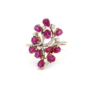 May include: A gold ring with a delicate design featuring a cluster of ruby and diamond stones. The ruby stones are pear-shaped and the diamonds are round.