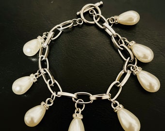 White pearl charms on a silver stainless steel link style bracelet.