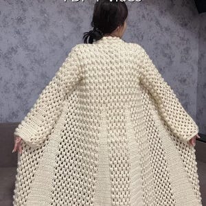 May include: Cream-colored, long crochet cardigan with a textured stitch pattern. The garment features a wide, flowing design and is displayed on a person. The image includes the text "Crochet Pattern PDF + video".