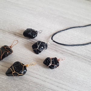 May include: Five black obsidian stone pendants wrapped in copper wire, with one pendant attached to a black cord necklace.
