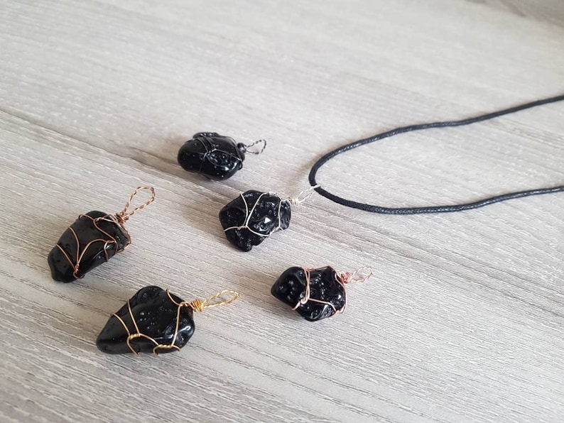 May include: Five black obsidian stone pendants wrapped in copper wire, with one pendant attached to a black cord necklace.