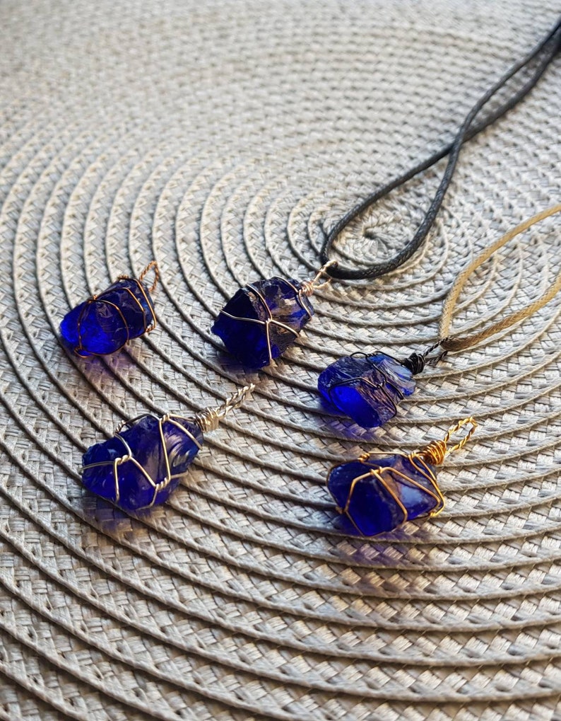 May include: Five cobalt blue glass pendants wrapped in gold wire, some on black and brown cords.