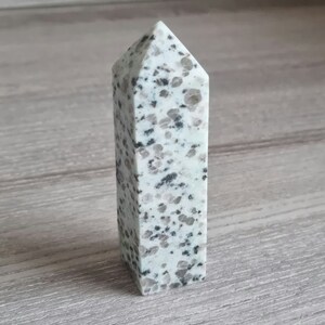 Puede incluir: Una punta de cristal blanca y gris moteada, también conocida como varita de cristal, con una punta puntiaguda y una base plana.