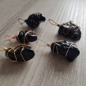 May include: Five black obsidian pendants wrapped in wire. The wire is gold, silver, and rose gold.