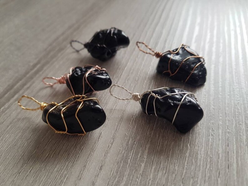 May include: Five black obsidian pendants wrapped in wire. The wire is gold, silver, and rose gold.