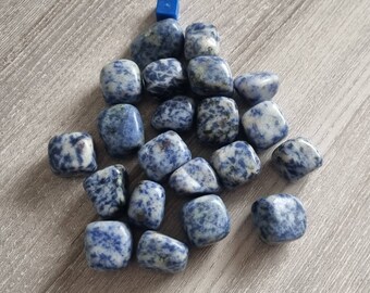 May include: A collection of tumbled blue and white sodalite stones. The stones are smooth and polished, with a variety of patterns and textures.