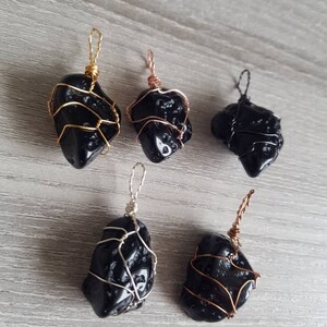 May include: Five black obsidian pendants wrapped in wire. The wire is gold, silver, and copper. The pendants are all different shapes and sizes.