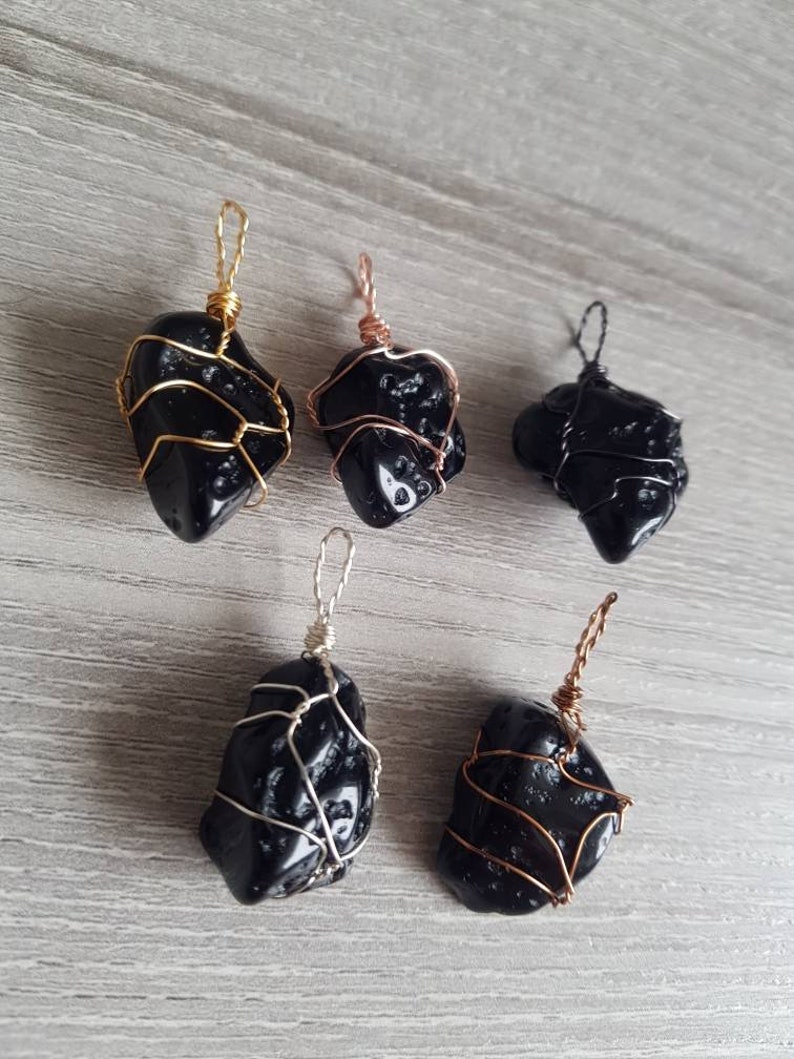May include: Five black obsidian pendants wrapped in wire. The wire is gold, silver, and copper. The pendants are all different shapes and sizes.
