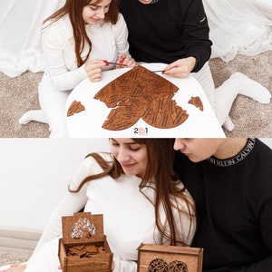 Puede incluir: Un rompecabezas de madera en forma de coraz&oacute;n con las palabras "2&1 Wedding" en la parte inferior. El rompecabezas tiene forma de coraz&oacute;n y est&aacute; hecho de muchas piezas peque&ntilde;as. Una pareja est&aacute; poniendo el rompecabezas junto.