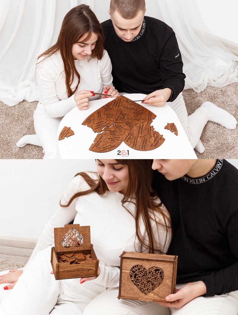 Puede incluir: Un rompecabezas de madera en forma de coraz&oacute;n con las palabras "2&1 Wedding" en la parte inferior. El rompecabezas tiene forma de coraz&oacute;n y est&aacute; hecho de muchas piezas peque&ntilde;as. Una pareja est&aacute; poniendo el rompecabezas junto.