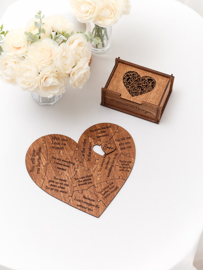 Puede incluir: Un rompecabezas de madera en forma de coraz&oacute;n con mensajes grabados sobre el amor y las relaciones. Las piezas del rompecabezas encajan para formar un coraz&oacute;n completo. El rompecabezas est&aacute; sobre una superficie blanca.