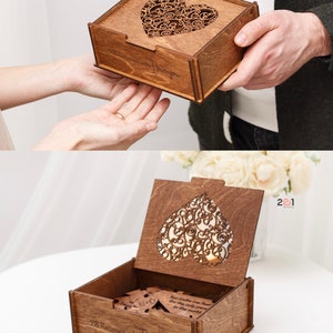 Puede incluir: Una caja de madera con un recorte en forma de coraz&oacute;n en la tapa. La caja est&aacute; abierta y contiene un conjunto de piezas de rompecabezas de madera que deletrean "28 razones por las que te amo".