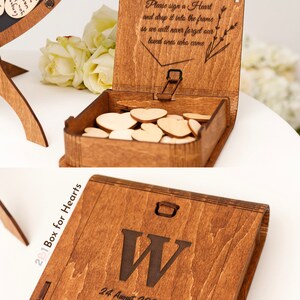 May include: A wooden box with a slot on the top for dropping in small wooden hearts. The box is engraved with the text "Box for Hearts", "24 August 2024", and the letter "W". The lid of the box is open and has the text "Please sign a Heart and drop it into the frame so we will never forget our loved ones who came."