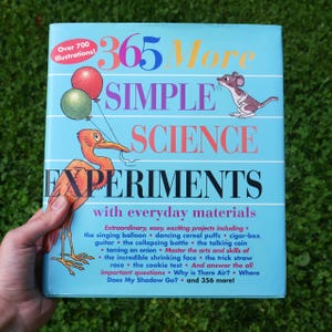 May include: A light blue book cover with the title "365 More Simple Science Experiments" and illustrations of a bird with balloons and a mouse. The cover also includes the text "Over 700 Illustrations!" and a list of experiments.
